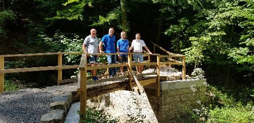 auf einer Holzbrücke im Wald stehen vier Männer