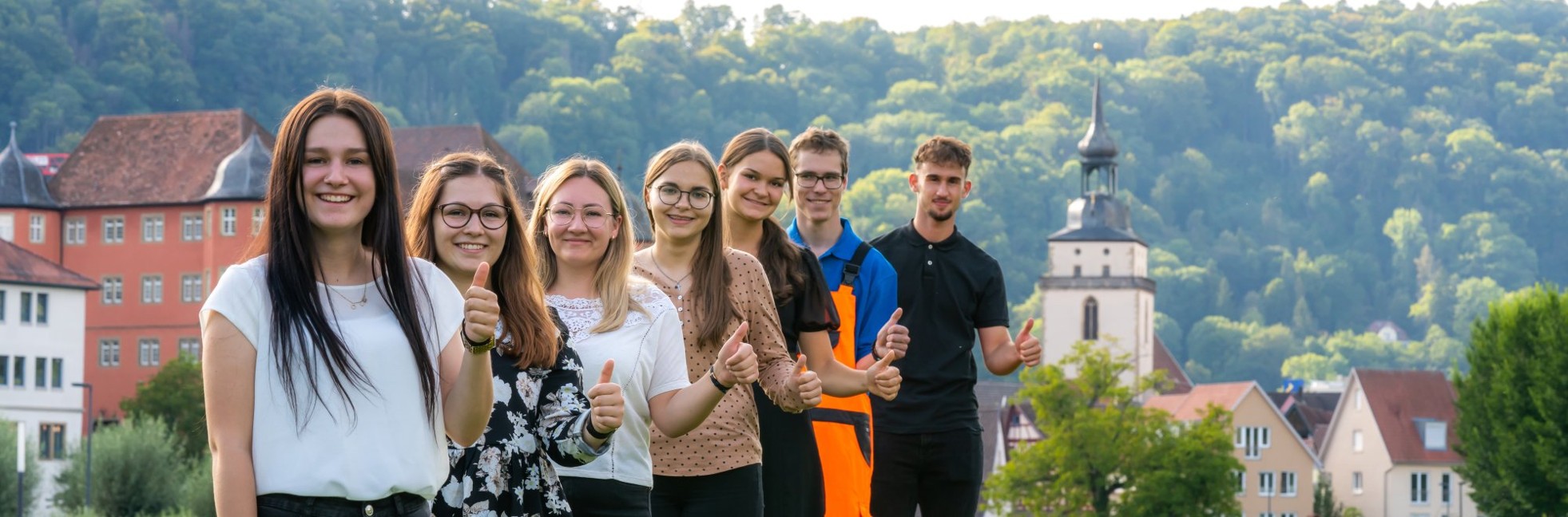 Auszubildende mit Daumen hoch vor Stadtkulisse