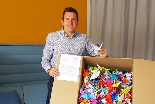 Bürgermeister Stefan Neumann mit einem Karton voll mit Papier-Kranichen.