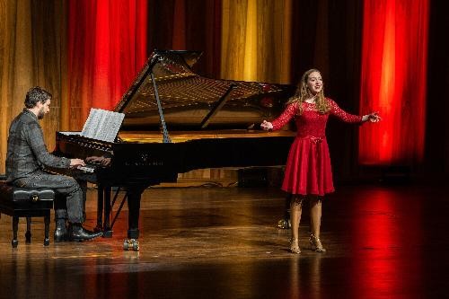 Eine Sängerin in rotem Kleid wird begleitet von einem Herrn am Klavier