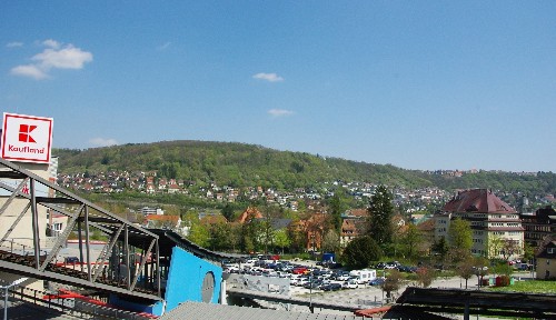 links ist der Talstation der Bergbahn und der Werbepylon des Kauflandes zu sehen,  in der Mitte Schotterparkplatz, rechts der Gebäudekomplexes des Landratsamtes