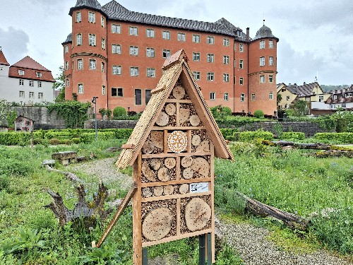 Bienenhotel im Hintergrund Grünfläche und Schloß Bartenau