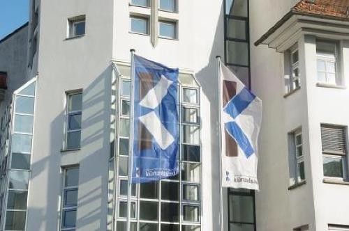 blau-weiße Flaggen wehen vor dem Rathausturm