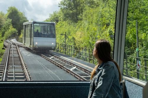 eine junge Frau sitzt in einem Bergbahnwaggon und blickt durch das große Fenster dem entgegenkommenden Waggon entgegen
