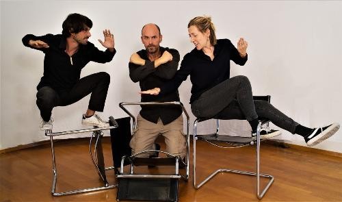 Drei gestikulierende Personen in schwarz gekleidet auf Stühlen