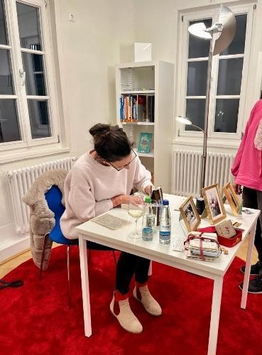 Lucinde Hutzenlaub sitzt an einem Tisch und unterschreibt Autogrammkarten in der Stadtbücherei Künzelsau