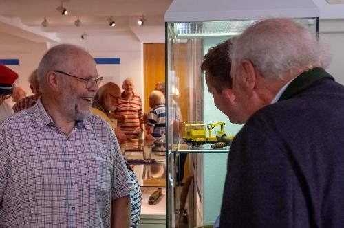 Besuchende bei der Ausstellungseröffnung schauen sich eine Miniatureisbahn