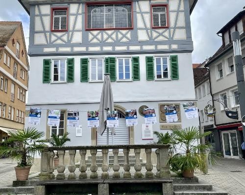 9 Plakate aufgehängt an einer Leine vor dem Alten Rathaus