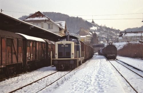 Blick auf drei Züge, die in einem Bahnhof stehen. Es liegt Schnee.