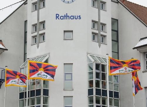 vier bunte Tibet-Fahnen bewegen sich im Wind, sind am Rathaus gehisst