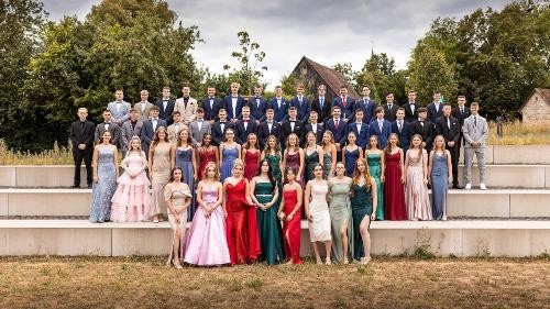 Viele junge Menschen stehen af Treppen und tragen schöne Kleider und Hemden.