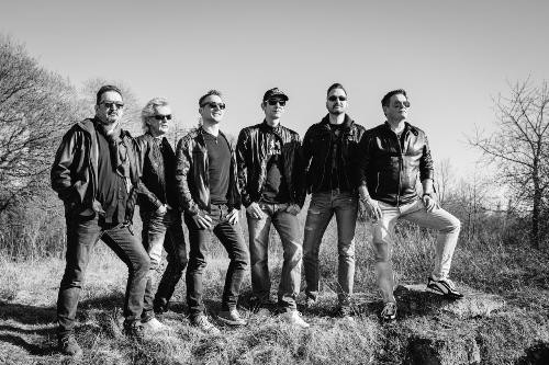 Ein schwarz/weiß Bild mit sechs Männern welche auf einem kleinen Hügel stehen.