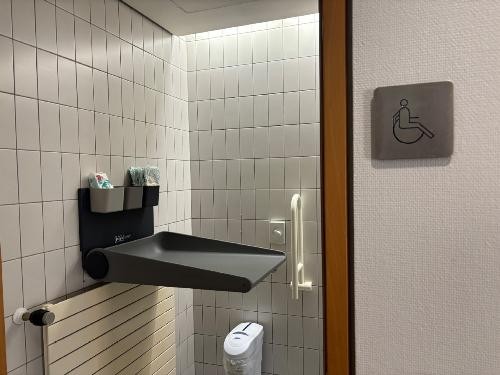 eine Ablage und die Wickelkommode in einem Badezimmer mit weißen Fliesen.