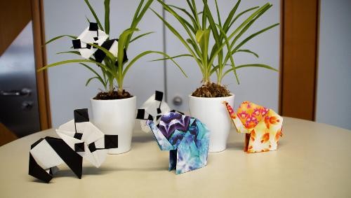 Auf einem Tisch liegen aus Papier gefaltete Panda und Elefanten Figuren.