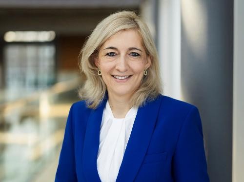 Porträtfoto der Ministerin. Sie trägt einen royalblauen Blaser darunter eine weiße Blus