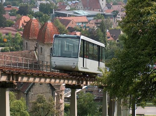 Ein Blick auf die graue Bergbahn mit einem Baum am rechten Bildrand und Künzelsau im Hintergrund.