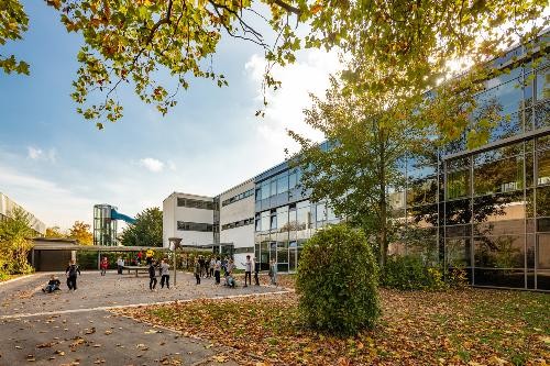 ein Schulhof mit der Schule nebendran. Kinder auf dem Pausenhof. Herbstliche stimmung