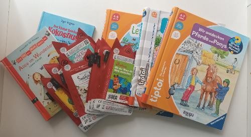 Viele Bücher liegen auf dem Tisch quer übereinander gelegt.