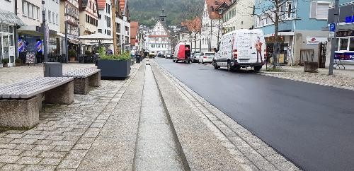Blick in die sanierte Hauptstraße: links die kleine Wasserinne, rechts der neue scharze Teerbelegt, im Hintergrund das Alte Rathaus