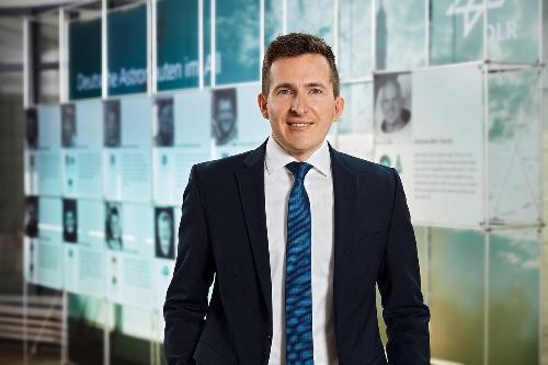 Bürgermeister Neumann im Porträtfoto, im dunklen Anzug mit blauer Krawatte