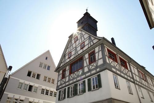Das Alte Rathaus in Künzelsau ist bei strahlendem Sonnenschein zu sehen; das historische Gebäude steht im Mittelpunkt und wird von hellem Tageslicht beleuchtet.