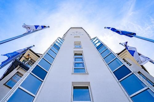 Ansicht des Rathaus Künzelsau aus einer niedrigen Perspektive: Das Gebäude wird von unten nach oben gezeigt, wodurch die Fassade, mehrere Fensterreihen und das Dach in den Blick rücken; der Himmel bildet den Hintergrund.