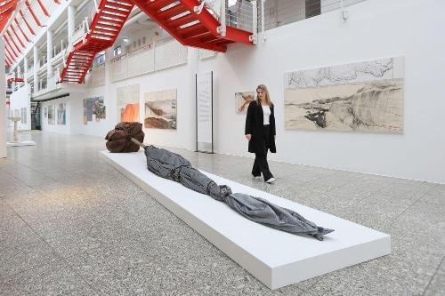 Ausstellungseinblick "Verhüllt, verschnürt, gestapelt - Christo und Jeanne-Claude. Sammlung Würth". Foto: Würth / Ufuk Arslan Das Bild zeigt eine Ausstellungsansicht mit einer Besucherin im Museum Würth. Es sind Kunstwerke von Christo und Jeanne-Claude ausgestellt.