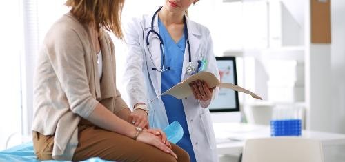 Ärztin hält Hand einer Patientin.