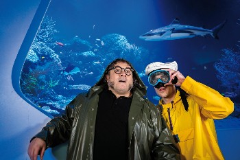 Zwei Männer vor einem Aquarium, einer mit Tauchbrille.