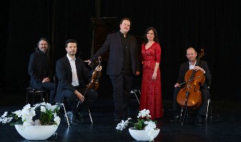 drei Musiker mit Cello, Geige und Klavier, sowie eine Sängerin und ein Sänger auf der Bühne