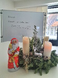 Adventsgesteck, Schokoladennikolaus, Spruch im HIntergrund.Advent