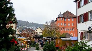 Bei Tag: Blick auf den Weihnachtsmarkt auf dem Schloßplatz mit der Bühne und dem Schloß im Hintergrund.