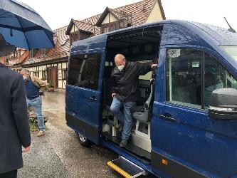 Ein älterer Mann steigt aus einem blauen Minibus aus