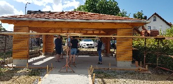 Holzpavillon mit Ziegeldach von außen, Baugerüst rechts