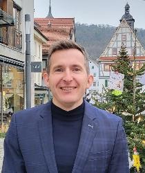 Porträtfoto von Bürgermeister Stefan Neumann, im HIntergrund Altes Rathaus und Weihnachtsbäume