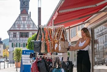 Eine Frau schaut sich Handtaschen in einer Auslage außen an einem Laden an 
