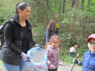 eine Frau und vier Kinder sammeln Müll im Wald