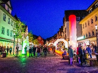 Blick in die Hauptstraße mit stimmungsvollem Licht und Leuchtobjekten mit Besuchern