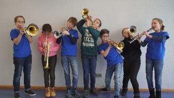 Sieben Kinder mit verschiedenen Instrumenten.