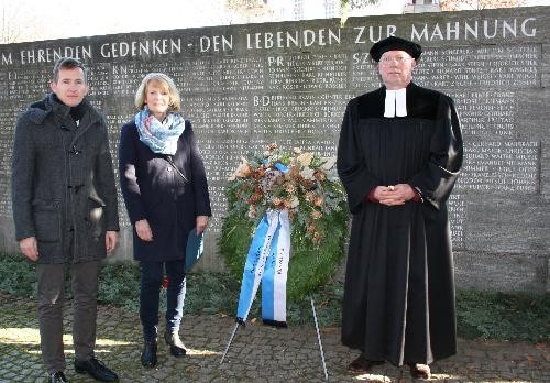 Einen Kranz auf dem Friedhof mit Bürgermeister Stefan Neumann, Dekan Dr. Friedemann Richert und Theresia Hackmann.