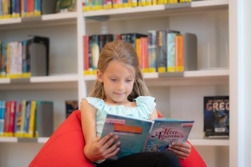 Ein Mädchen liest in der Stadtbücherei ein Buch.