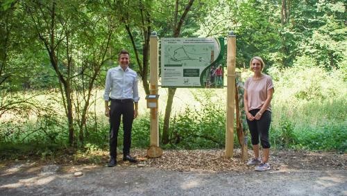 Bürgermeister Stefan Neumann und Diana Gleiter vom Projektteam stehen neben dem Schild zum Natur-Erlebnis-Pfad.