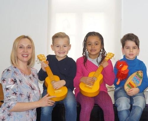 Drei Kinder mit Musikinstrumenten und ihre Lehrerin.