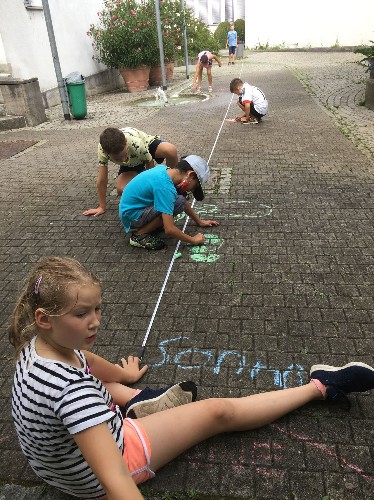 Kinder malen Planetensystem auf den Boden.