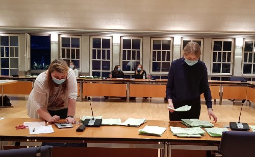 Zwei Wahlhelferinnen zählen Stimmzettel im großen Sitzungssaal.