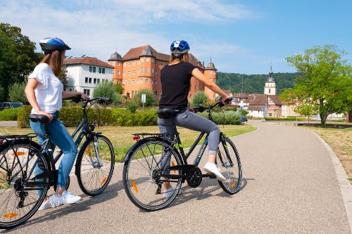 Zwei Fahrradfahrerinnen in den Wertwiesen vor dem Schloss.