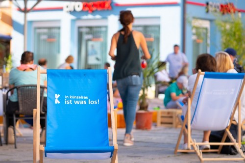 Im Vordergrund ein blauer Liegstuhl mit Künzelsau-Logo.