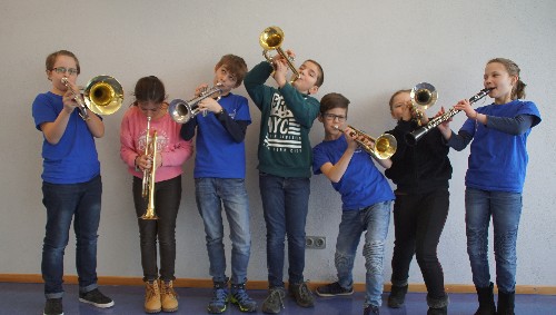 7 Jugendliche mit verschiedenen Blasinstrumenten
