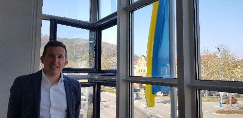 Bürgermeister Stefan am Fenster im Rathausturm mit Flagge im Hintergrund.