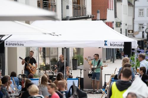 Band mit Zuhörern an Tischen in der Hauptstraße.